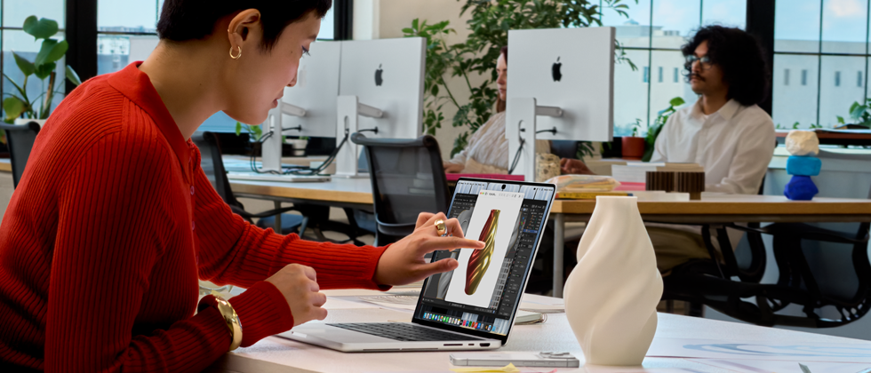 Una persona in un ufficio open space usa il Touch per interagire con un MacBook Pro con display PROLED XDR