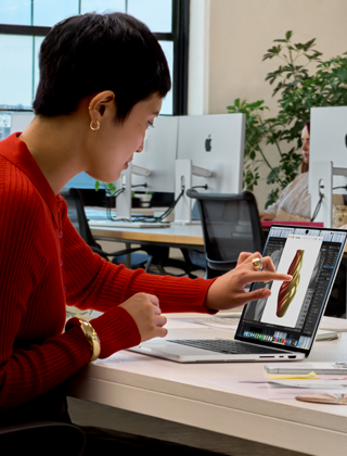 Una persona in un ufficio open space usa il Touch per interagire con un MacBook Pro con display PROLED XDR