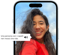 Un iPhone 15 con la funzione VoiceOver che descrive una fotografia: una persona con i capelli neri mossi che ride