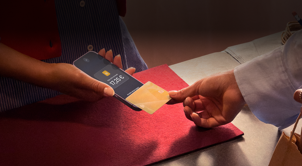 Una mano che appoggia una carta di credito a un iPhone per completare una transazione