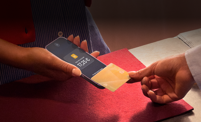 Una mano che appoggia una carta di credito a un iPhone per completare una transazione