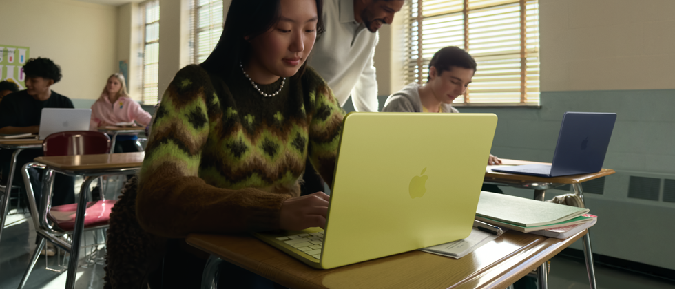 Studente che usa un MacBook Neo giallo agrume non collegato alla corrente sul banco di un’aula